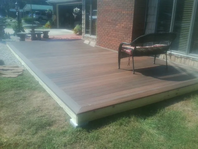 New wood deck and wicker chair beside a brick house in New Oxford