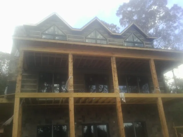 Dormers and porch framing on a large log home under construction — Roof Coating work by our crew in New Oxford