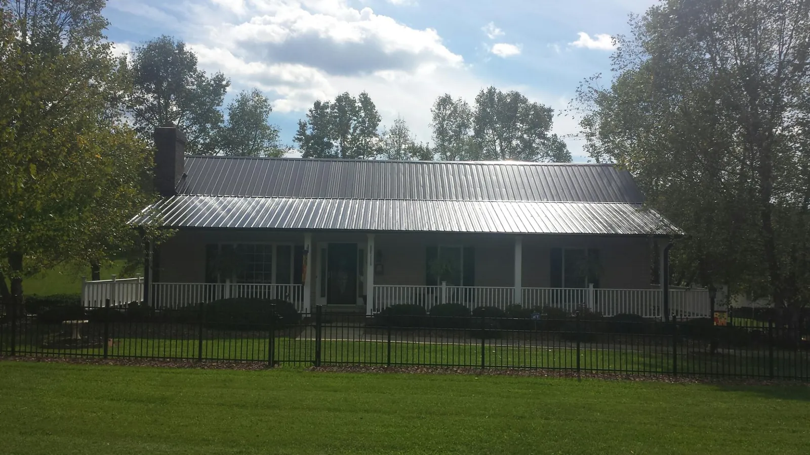 Gray metal roof on a brick ranch with a full width front porch — Gutter Guard Installation work by our crew in New Oxford