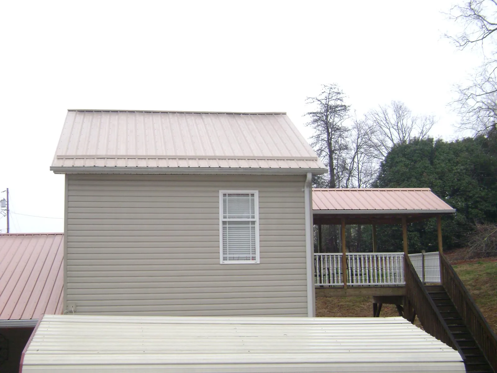 Tan metal roofs on a two story addition and attached porch, from a Roof Replacement job in New Oxford